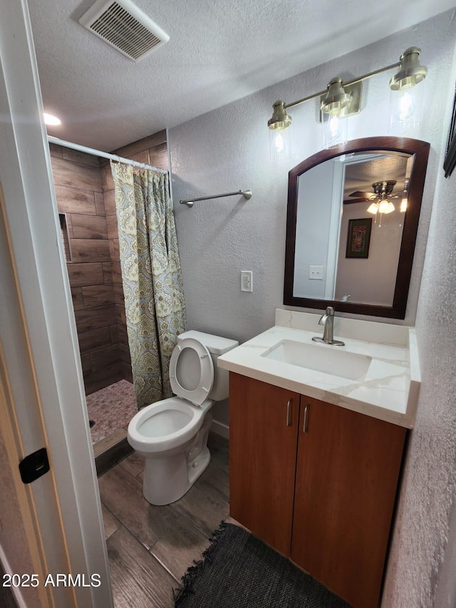 bathroom with a textured ceiling, wood-type flooring, ceiling fan, a shower with shower curtain, and vanity