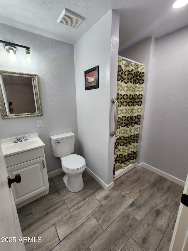 bathroom featuring toilet, vanity, a textured ceiling, and a shower with curtain