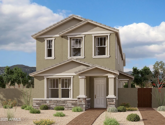 view of front of house with stone siding, fence, a tile roof, and stucco siding