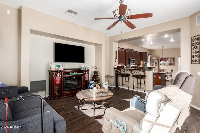 living room featuring ceiling fan, a fireplace, and dark hardwood / wood-style floors