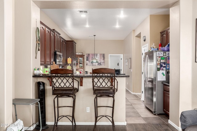 kitchen featuring pendant lighting, kitchen peninsula, a breakfast bar area, and appliances with stainless steel finishes