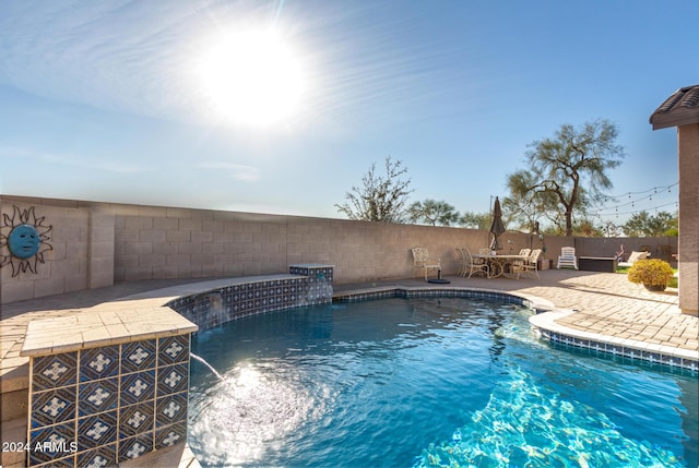 view of swimming pool with pool water feature and a patio