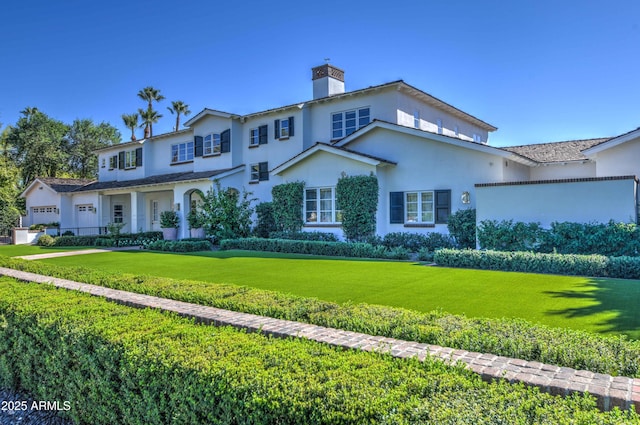 view of front of house with a front lawn, a chimney, and stucco siding