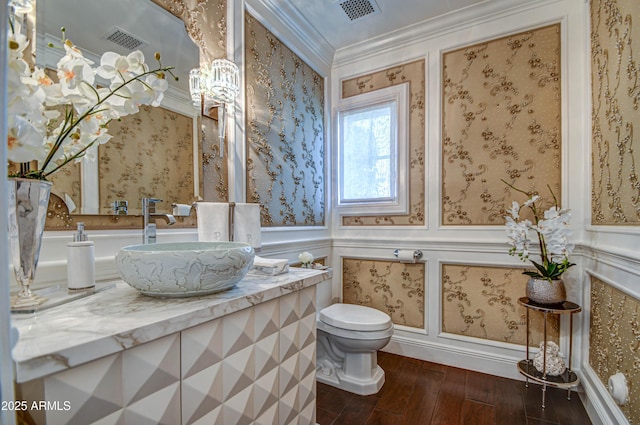 bathroom with hardwood / wood-style flooring, ornamental molding, toilet, and vanity