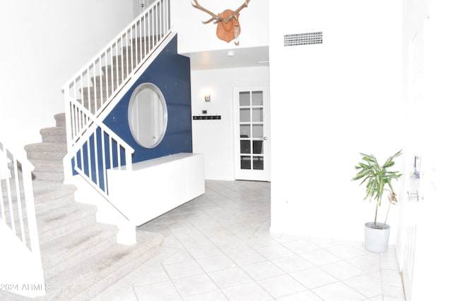 staircase with french doors, tile patterned flooring, and a high ceiling