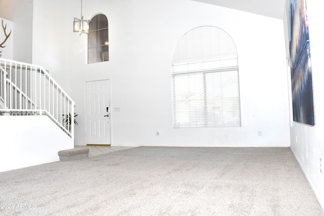 entrance foyer featuring carpet flooring, a notable chandelier, and a high ceiling