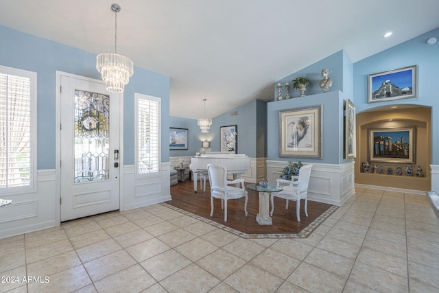 dining area featuring a chandelier, vaulted ceiling, and light tile patterned flooring