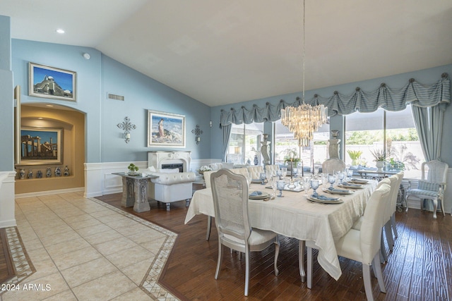 dining room featuring a notable chandelier, light hardwood / wood-style floors, a healthy amount of sunlight, and vaulted ceiling