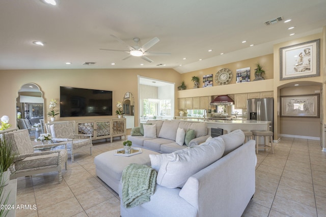 living room featuring lofted ceiling, light tile patterned floors, and ceiling fan