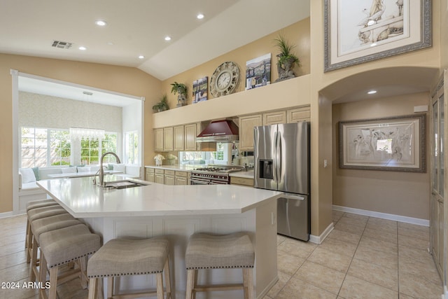 kitchen with appliances with stainless steel finishes, sink, an island with sink, wall chimney exhaust hood, and vaulted ceiling