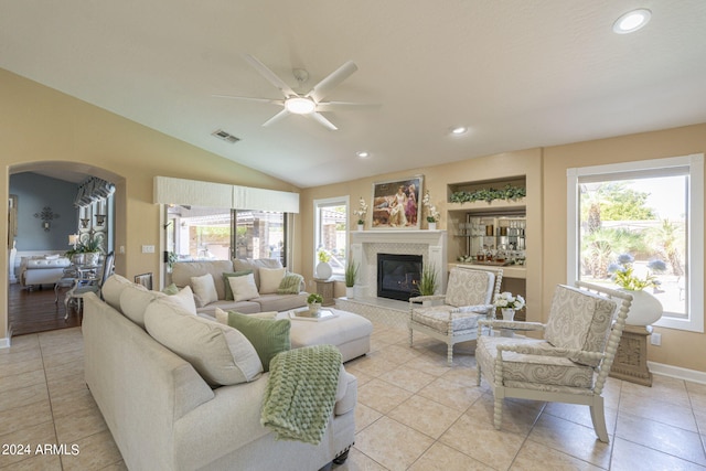 living room featuring lofted ceiling, light tile patterned flooring, and ceiling fan