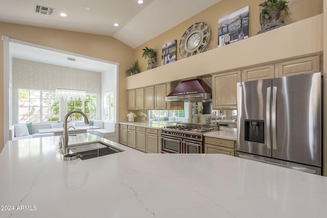 kitchen featuring wall chimney exhaust hood, sink, light stone countertops, vaulted ceiling, and appliances with stainless steel finishes