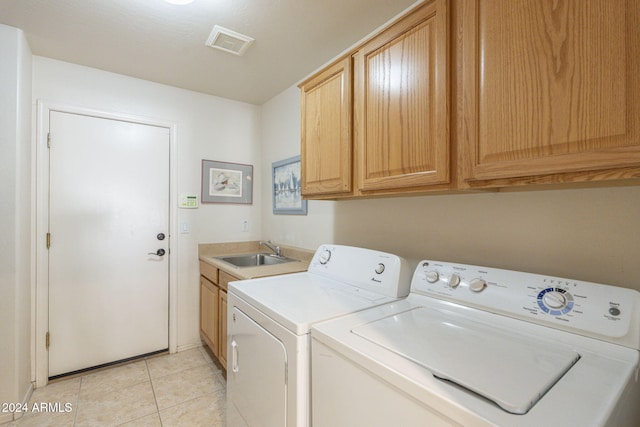 laundry room featuring light tile patterned flooring, cabinets, sink, and washing machine and clothes dryer