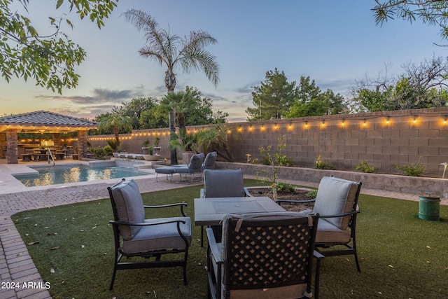 patio terrace at dusk with a fenced in pool, a gazebo, and a yard