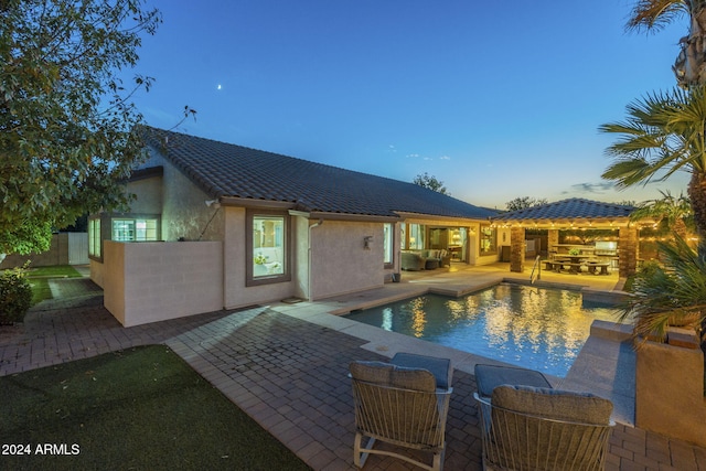 pool at dusk with a patio area and outdoor lounge area