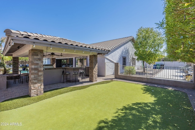 exterior space featuring area for grilling, ceiling fan, exterior bar, and a patio area