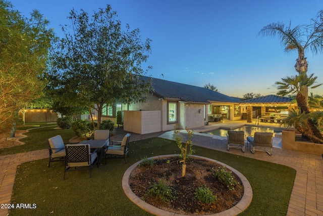 back house at dusk with a yard and a patio