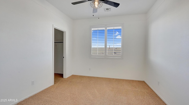 unfurnished bedroom featuring a walk in closet, a closet, ceiling fan, and carpet