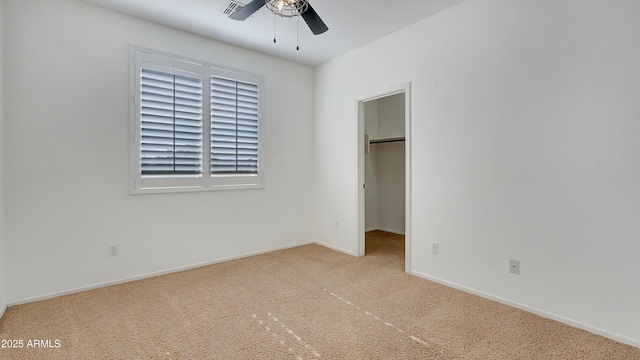 unfurnished bedroom featuring a spacious closet, light carpet, ceiling fan, and a closet