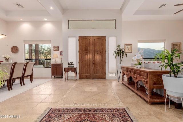 foyer entrance featuring a mountain view, a towering ceiling, ceiling fan, and a raised ceiling