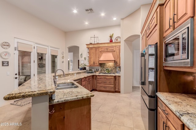 kitchen with custom range hood, sink, light tile patterned floors, decorative backsplash, and stainless steel appliances