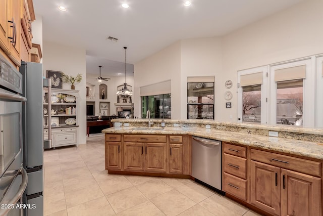 kitchen with light stone countertops, appliances with stainless steel finishes, sink, hanging light fixtures, and light tile patterned floors