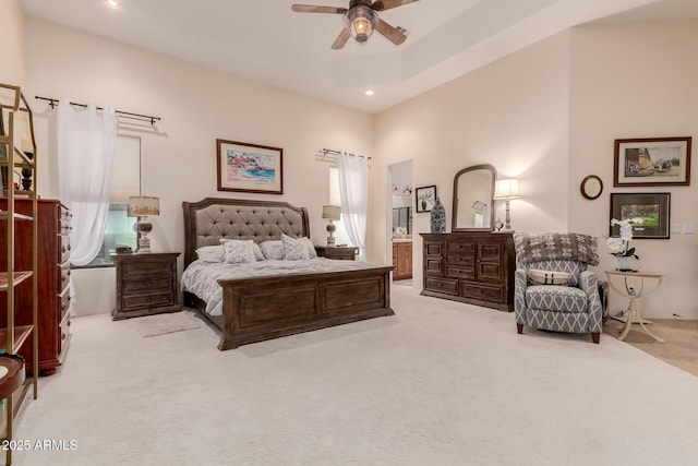 bedroom with ceiling fan, connected bathroom, a towering ceiling, and light carpet