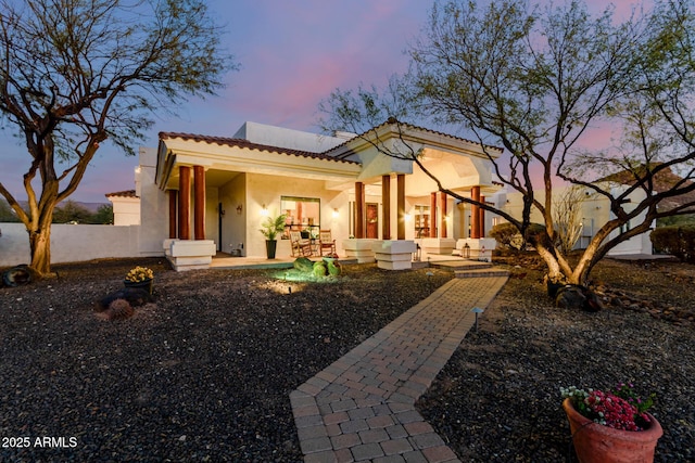 back house at dusk featuring a patio