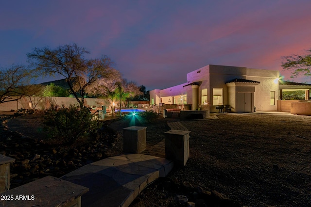 yard at dusk featuring a pool and a patio