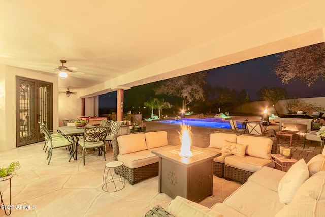 view of patio / terrace with ceiling fan and an outdoor living space with a fire pit