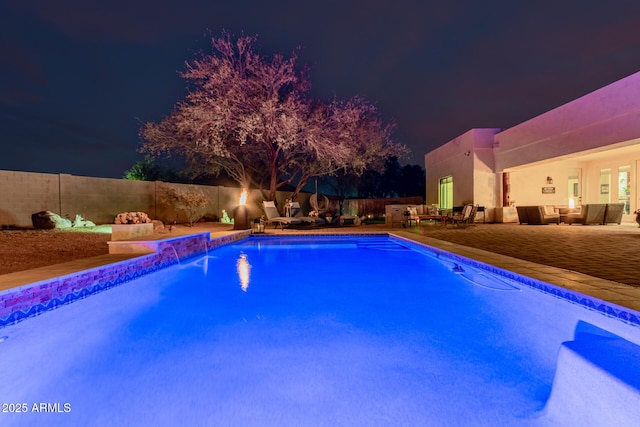 pool at twilight featuring a patio area, an outdoor hangout area, and pool water feature