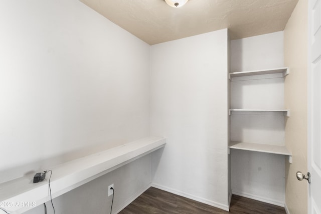 walk in closet with dark hardwood / wood-style flooring and built in desk