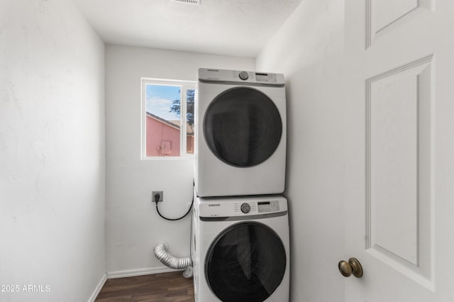 clothes washing area featuring dark hardwood / wood-style floors and stacked washer and clothes dryer