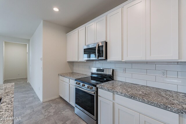 kitchen featuring light stone counters, stainless steel appliances, white cabinetry, and sink