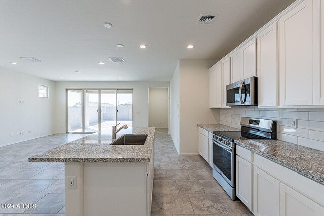 kitchen featuring sink, tasteful backsplash, a center island with sink, white cabinets, and appliances with stainless steel finishes