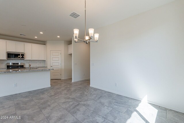 kitchen with white cabinets, decorative light fixtures, light stone counters, and appliances with stainless steel finishes