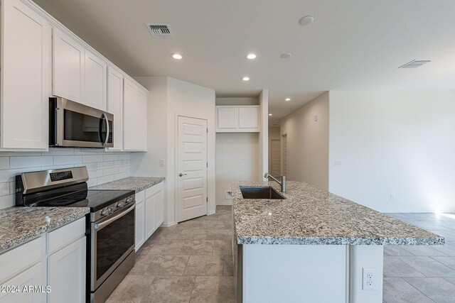 kitchen featuring white cabinets, appliances with stainless steel finishes, a center island with sink, and sink