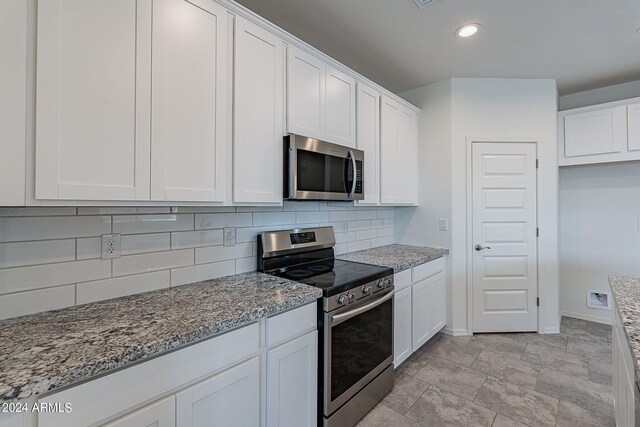 kitchen featuring stainless steel appliances, white cabinetry, and light stone counters