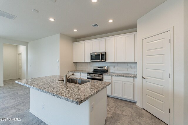 kitchen featuring backsplash, light stone countertops, white cabinets, and appliances with stainless steel finishes