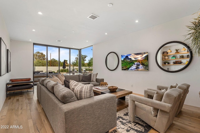 living area featuring recessed lighting, visible vents, light wood-style flooring, and floor to ceiling windows