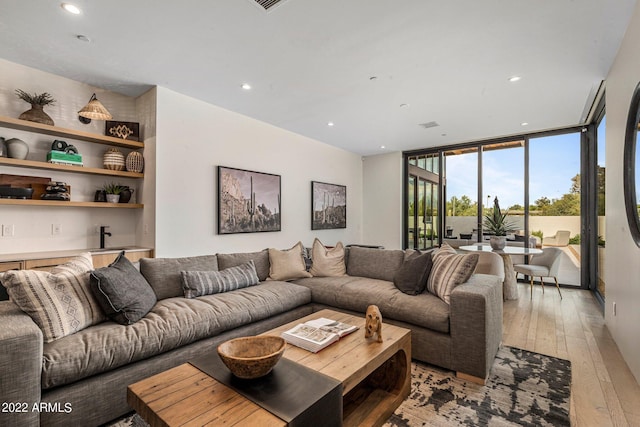 living room with floor to ceiling windows, recessed lighting, and light wood-style flooring
