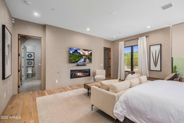 bedroom featuring light wood finished floors, visible vents, access to exterior, recessed lighting, and a glass covered fireplace