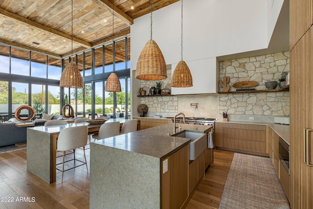 kitchen with modern cabinets, hardwood / wood-style flooring, a sink, a high ceiling, and wooden ceiling