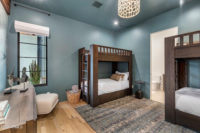 bedroom with visible vents, ensuite bath, and wood finished floors