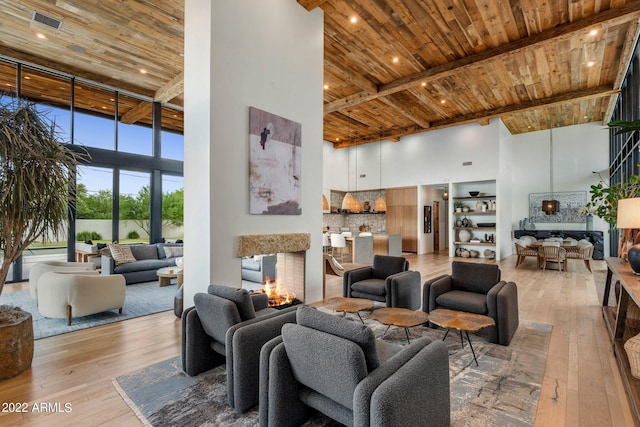 living area featuring wooden ceiling, a high ceiling, a multi sided fireplace, and light wood-type flooring