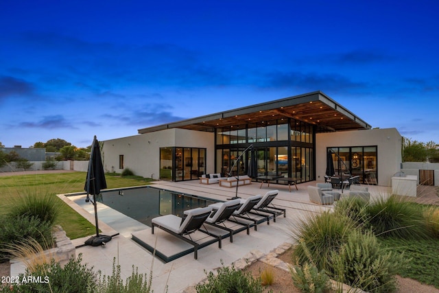 back of property with a patio area, stucco siding, a yard, and a fenced in pool