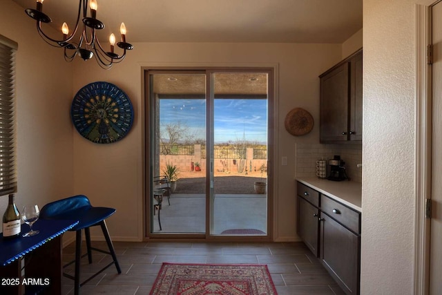 doorway with an inviting chandelier and baseboards