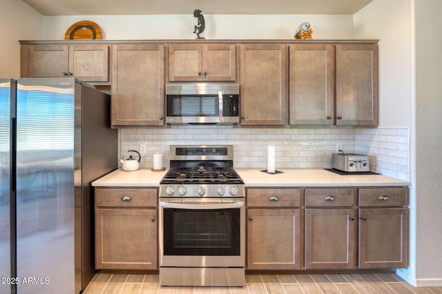 kitchen featuring wood tiled floor, appliances with stainless steel finishes, decorative backsplash, and light countertops