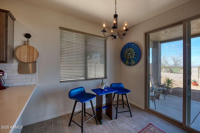 dining area with baseboards, a notable chandelier, and wood tiled floor