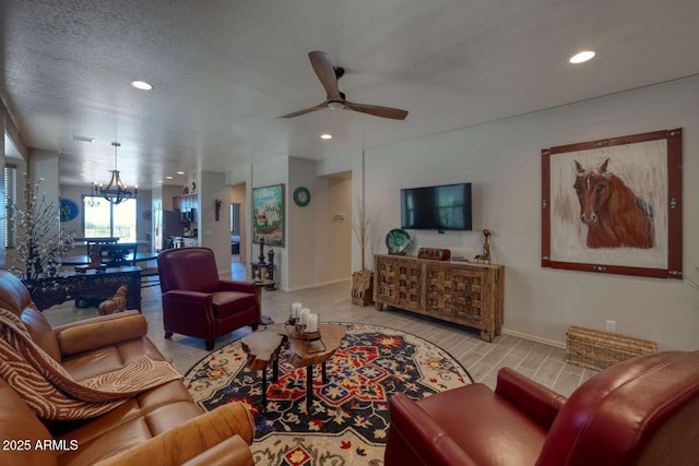 living room with a textured ceiling, ceiling fan with notable chandelier, baseboards, and recessed lighting